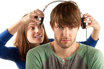 Pretty young woman interupts man with headphones